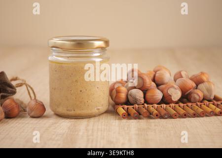 Hazelnut spread in jar with hazelnuts on wooden table Stock Photo