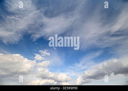 High cirrus streaks above clouds, delicate feathered patterns radiate across bright sky, sense of elevation and motion with layered textures ideal for Stock Photo