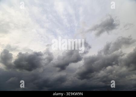 Stormy sky brewing. Dark clouds gather overhead. Gray thunderclouds drift across expansive sky. Approaching storm with thick clouds and ominous atmosp Stock Photo