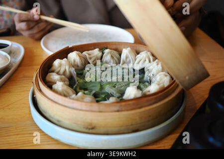 Dumplings in a bamboo steamer on a wooden table Stock Photo