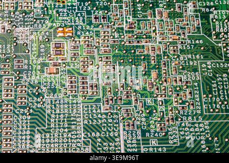 Detailed macro of printed circuit board with dense electronic components and connections. Abstract technology background showing complexity of modern Stock Photo