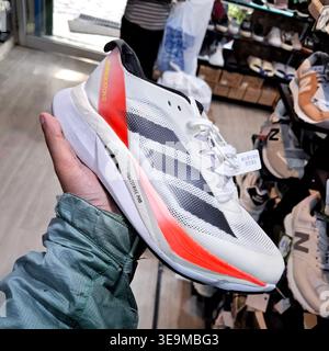 Modern athletic running shoe in hand, showcasing design and vibrant details in a store setting Stock Photo