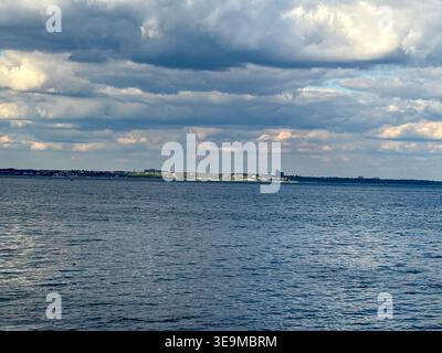 Distant City Skyline and Moody Ocean View Under Dramatic Cloudscape Stock Photo