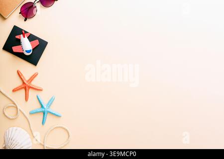 Travel items with toy airplane, seashells and sunglasses on beige background with copy space. Top view, flat lay Stock Photo