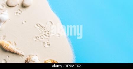 Seashells and starfish on sandy beach with blue water. Top view, flat lay, copy space Stock Photo