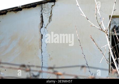 Deep crack in an old plaster wall of a damaged building. Concept of structural failure, poor maintenance, earthquake damage, or need for repair and re Stock Photo