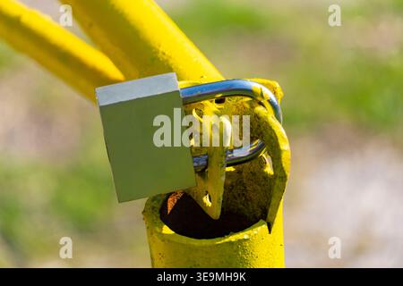 Close-up of a padlock on a yellow metal barrier gate. Concept of security, restricted access, protection and private property Stock Photo