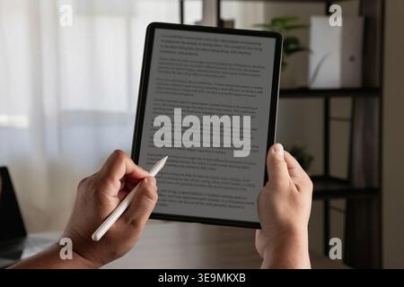 Hands using stylus on tablet displaying text document, writing and editing content for document creation, text processing, content management, and dig Stock Photo