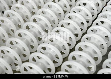 White plastic rollers of industrial conveyor, production, sorting, or transportation line, close-up shot, abstract background Stock Photo