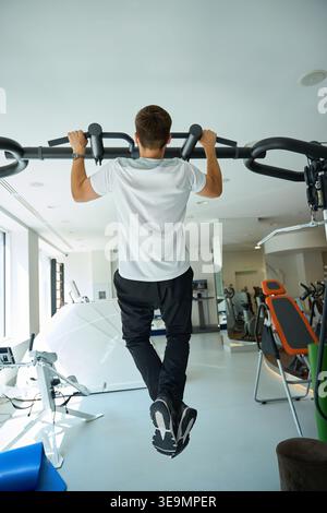 Focused man doing pull-ups in modern indoor gym Stock Photo
