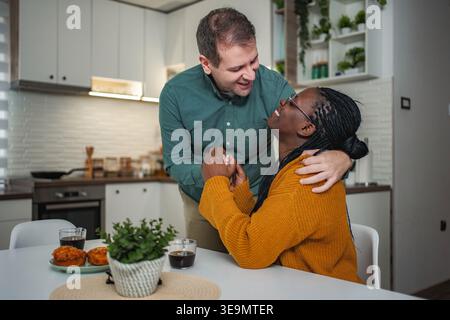 Interracial couple sharing happy morning moments in kitchen Stock Photo