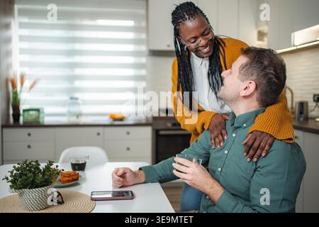 Interracial couple sharing happy morning moments in kitchen Stock Photo