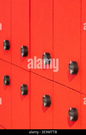 Storage lockers with code locks placed on bright red wall in modern interior. Stock Photo