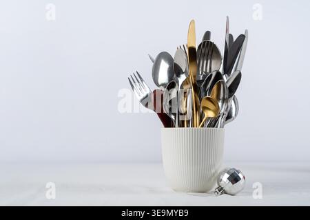 Happy new year, merry christmas. Set of cutlery of spoons, knives and forks in cup with holiday decorations on dining table, copy space Stock Photo