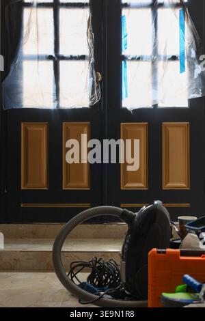 Residential renovation interior showing cleaning tools, covered glass panels, and doorway during maintenance work. Ideal for repair and remodelling Stock Photo