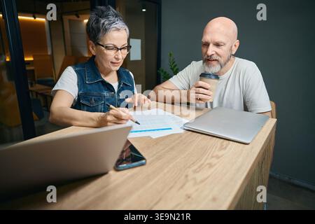 Middle-aged man and woman collaborating in office at night Stock Photo