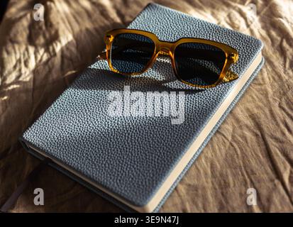 A pair of sunglasses sitting on a notebook. Stock Photo