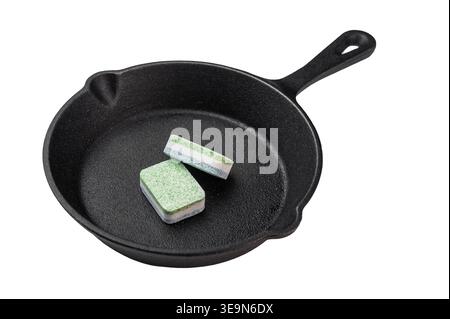 Dishwasher detergent tablets inside cast iron pan on dark background creative metaphor of cleaning versus cooking concept. Stock Photo
