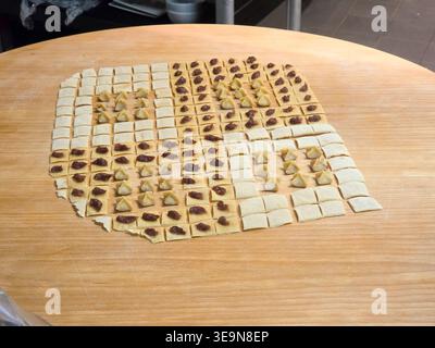 Step in preparation process , cooking process of manti (Turkish "ravioli", dumplings) with meat, laid out on a wooden table Stock Photo