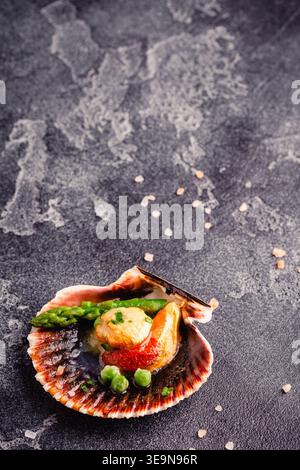 Cooked scallops with vegetables on a dark background Stock Photo