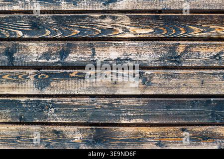 Weathered wooden planks with peeling dark paint. Natural wood grain and texture visible. Rustic horizontal surface, aged and worn. Ideal for backgroun Stock Photo