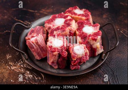 Raw Oxtail pieces in pan with fresh thyme, top view rustic food scene showing collagen rich beef for stock. Stock Photo