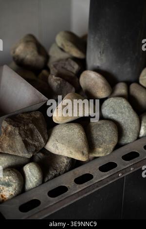 Close up view of natural stone rocks piled on a heater element, generating heat and steam in a Finnish sauna Stock Photo