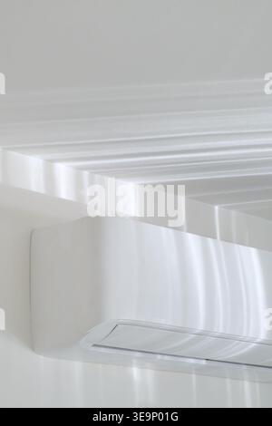 AC unit on white wall with sunlight reflections, minimal interior background, soft caustic light Stock Photo