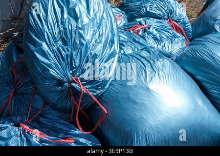 Blue plastic garbage bags tied with red strings are stacked together showing waste collection detail Stock Photo