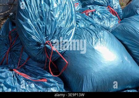 Close-up of blue garbage bags tied with red strings showing plastic waste and texture detail Stock Photo