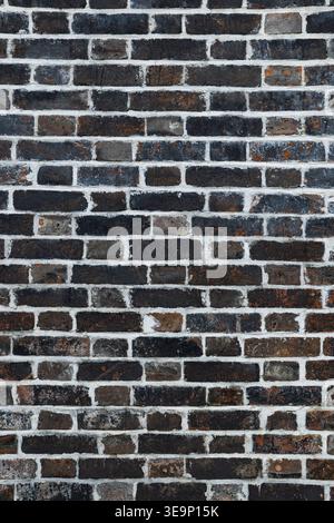 Dark brick wall with white mortar creating an abstract background surface Stock Photo