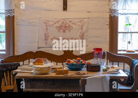 Rustic wooden table displaying colorful Easter eggs, traditional bread, and dyeing tools in a folk dwelling Stock Photo