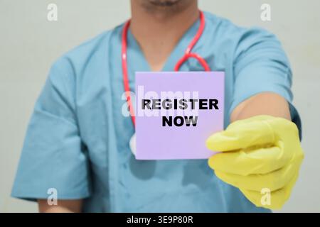 Doctor holds in hands a card with the name of the register now. Medical concept Stock Photo