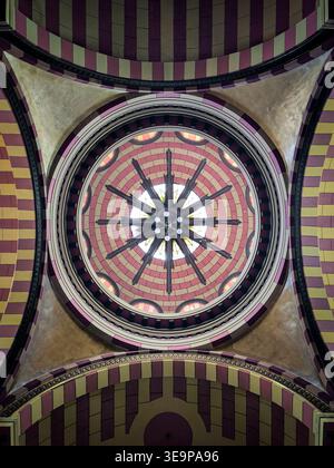 Looking up at a symmetrical dome ceiling with circular patterns and religious star motifs. Ornate architectural detail in pink, yellow, and gold tones Stock Photo