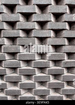A brick wall with a pattern of squares. The wall is gray and has a rough texture. The pattern is made up of small bricks that are arranged in a way th Stock Photo