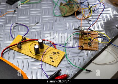 A bunch of wires and electronic components are on a grey surface. The wires are tangled and the components are scattered. Scene is chaotic and disorga Stock Photo