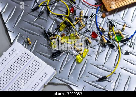 A pile of electronic components on a metal surface. The components include wires, resistors, and capacitors. Concept of disorganization and chaos, as Stock Photo