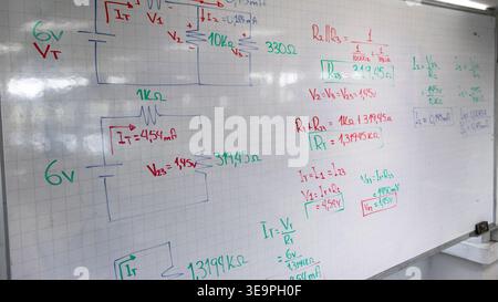 Close-up of hand-drawn electronic circuit schematics on a grid whiteboard. Showing resistors, voltage symbols, and current calculations for engineerin Stock Photo