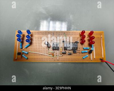 A circuit board with a bunch of LEDs on it. The board is made of wood and has a green wire running through it Stock Photo
