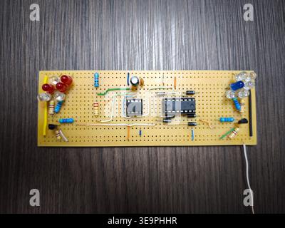 A circuit board with a bunch of LEDs on it. The board is made of wood and has a green wire running through it Stock Photo