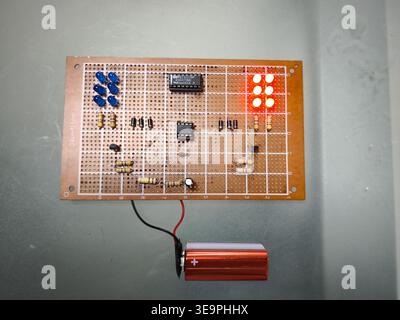A circuit board with a bunch of LEDs on it. The board is made of wood and has a green wire running through it Stock Photo