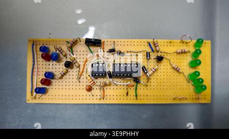 A circuit board with a bunch of LEDs on it. The board is made of wood and has a green wire running through it Stock Photo