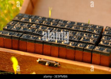 Detailed side close up dark rubber alphabet blocks in their orange-brown wooden box, emphasizing texture Stock Photo