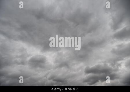 Cloudy sky textured with soft layers, gentle gradation of gray tones, subtle light filtering, serene atmosphere ideal for backgrounds and nature conce Stock Photo