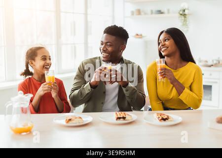 Family Enjoys Orange Juice and Pastries During Morning Gathering in Bright Kitchen Setting Stock Photo
