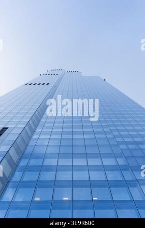 Low angle view of modern glass skyscraper against blue sky Stock Photo