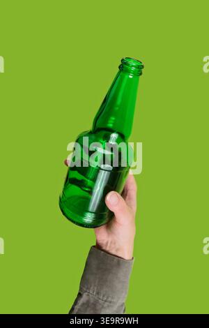 Hand holding green glass bottle on eco background Stock Photo