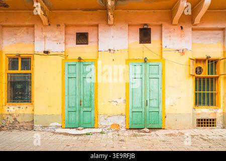 Old yellow building facade with green doors and windows in Serbia Stock Photo