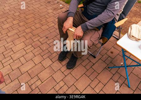 Seated Man Holding Knitted Wool Sock Outdoors Stock Photo