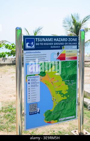 This vertical editorial image features a detailed bilingual (Thai and English) tsunami safety sign mounted on steel poles. The map highlights specific Stock Photo